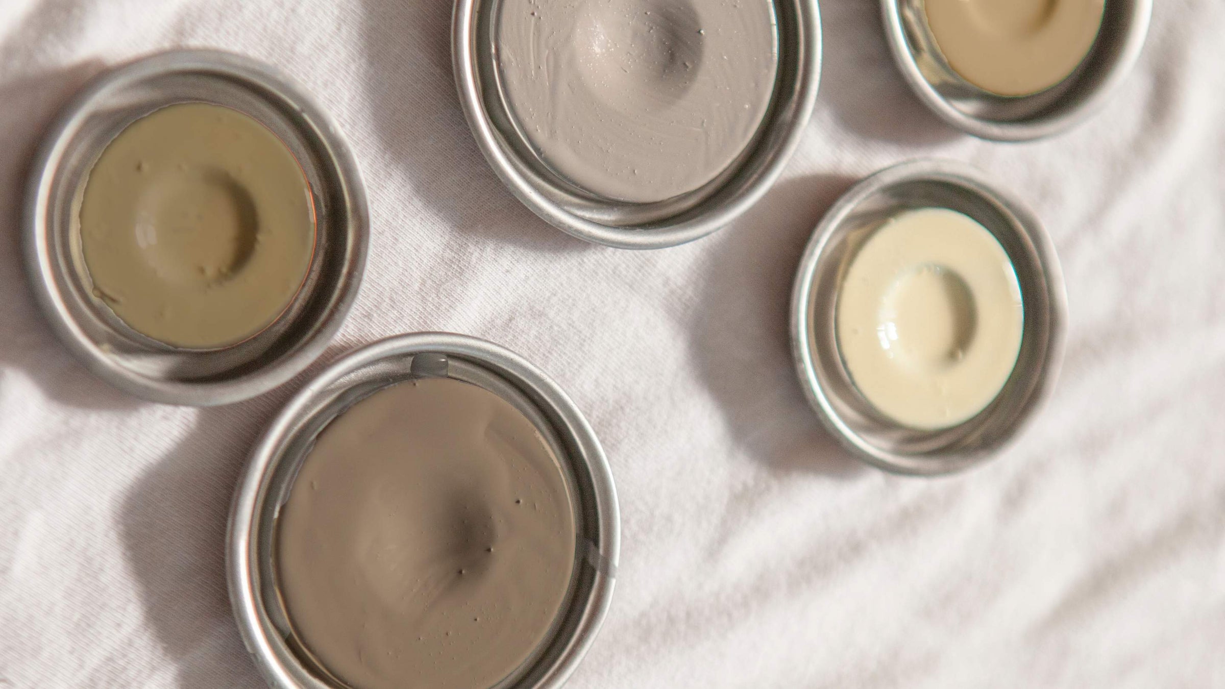 Top view of paint tin lids on white linen - Infusion Home